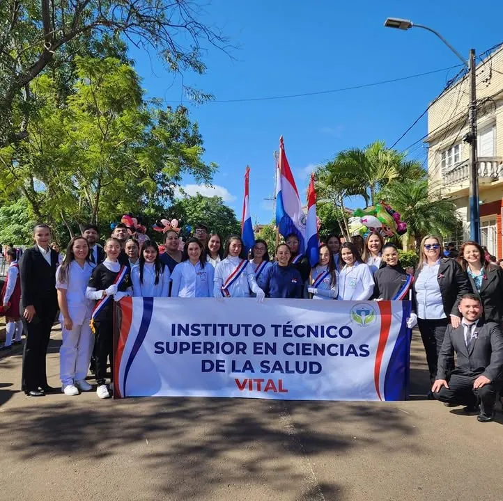 Estudiantes del ITS Vital con uniforme sosteniendo la bandera del instituto